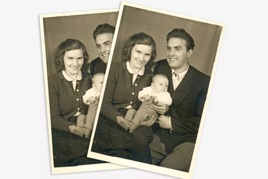 Zwart-wit foto van een glimlachend gezin met een moeder, vader en baby samen op een stoel
