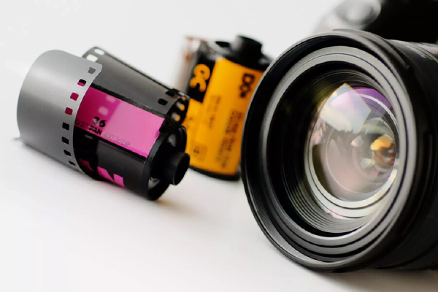 Close-up van een zwarte camera lens en twee filmrolletjes, klaar om mooie herinneringen vast te leggen