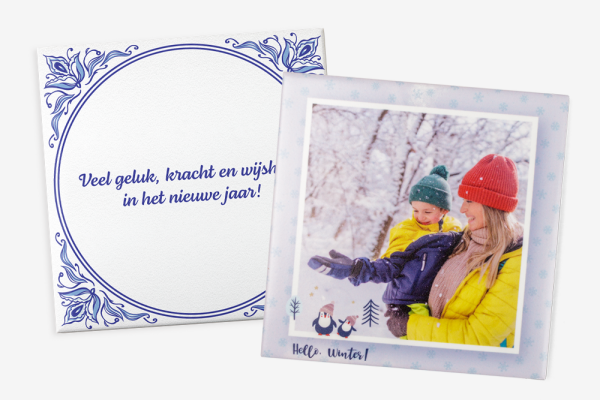 Vrouw met gele jas en rode muts houdt kind in gele jas en groene muts vast in een besneeuwd bos